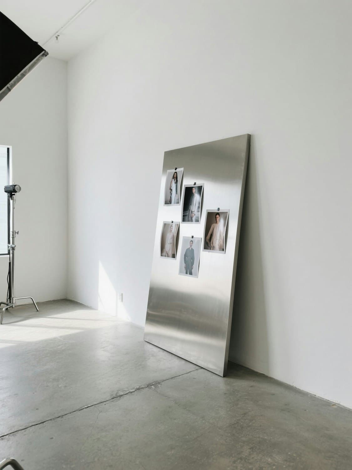 Fashion photographs pinned to a steel board in a bright studio